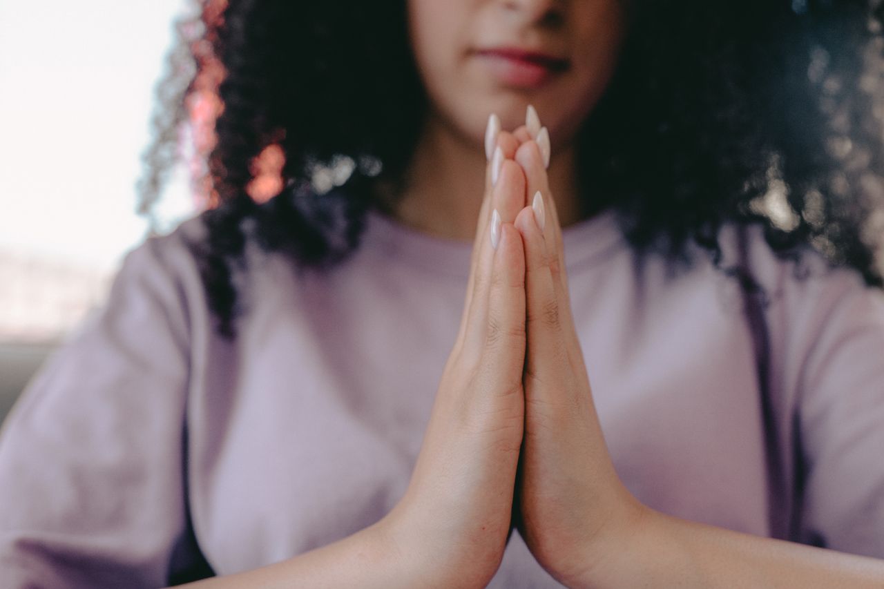 A serene close-up image of a woman with hands in a praying position, emphasizing mindfulness and calmness.